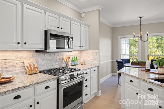 kitchen featuring backsplash, an inviting chandelier, ornamental molding, white cabinetry, and stainless steel appliances