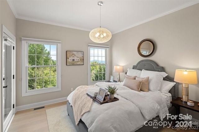 bedroom with crown molding, light hardwood / wood-style flooring, and an inviting chandelier