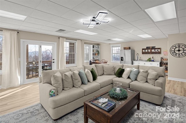 living room featuring light hardwood / wood-style flooring and a drop ceiling