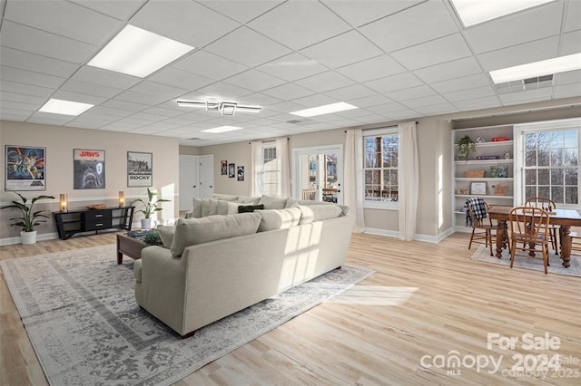 living room featuring a drop ceiling and light hardwood / wood-style floors