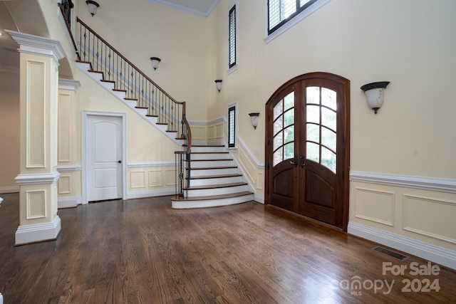 foyer entrance with french doors, dark hardwood / wood-style floors, ornate columns, and crown molding