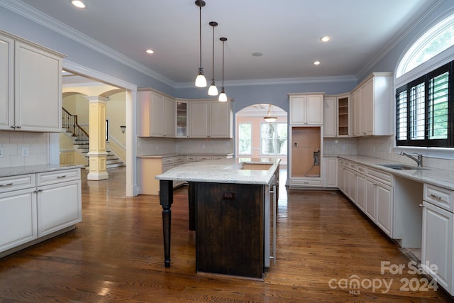 kitchen with pendant lighting, a kitchen breakfast bar, dark hardwood / wood-style floors, a kitchen island, and light stone counters