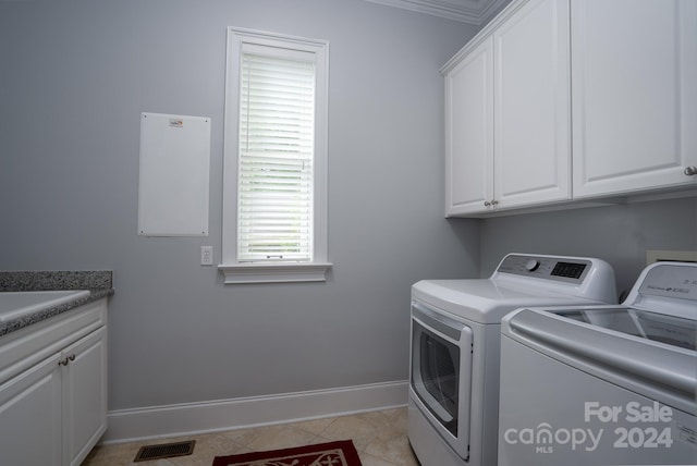 laundry area with light tile patterned flooring, cabinets, ornamental molding, and washing machine and clothes dryer