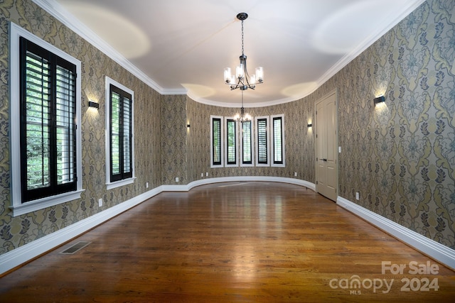 unfurnished dining area featuring hardwood / wood-style flooring, ornamental molding, and an inviting chandelier