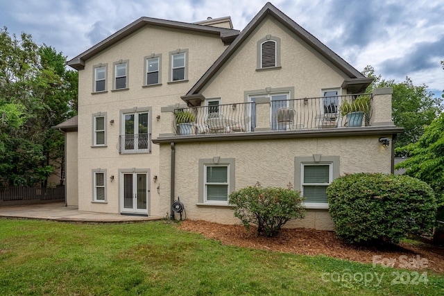 rear view of property with a lawn, a patio area, and a balcony