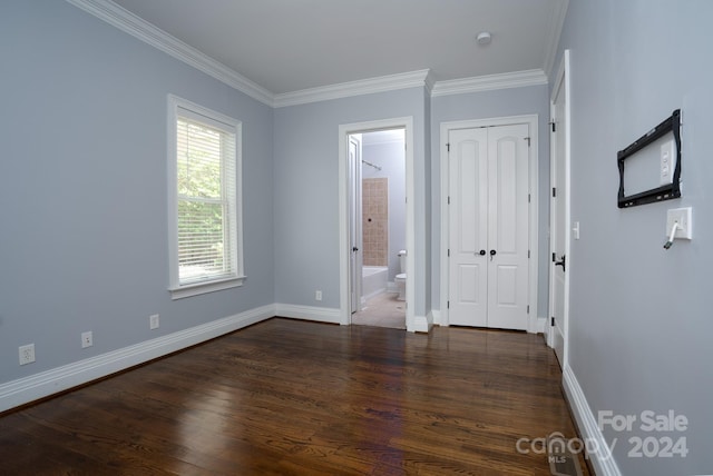 unfurnished bedroom featuring dark hardwood / wood-style flooring, crown molding, and connected bathroom