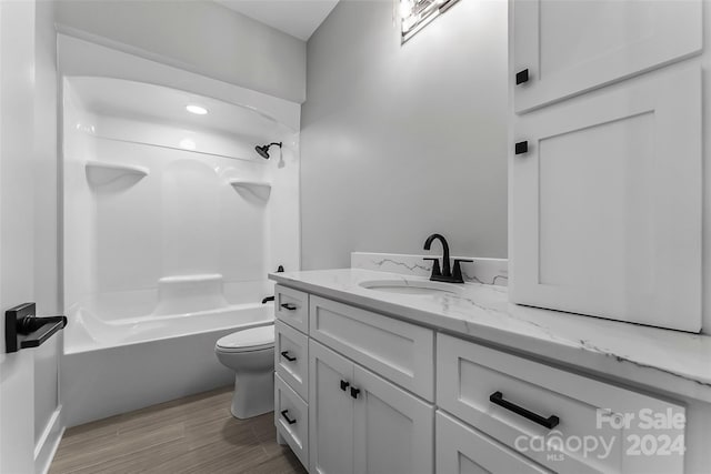 full bathroom with hardwood / wood-style flooring, vanity, shower / bathtub combination, and toilet