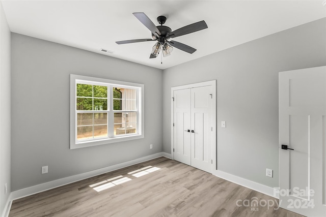 unfurnished bedroom with a closet, light hardwood / wood-style floors, and ceiling fan