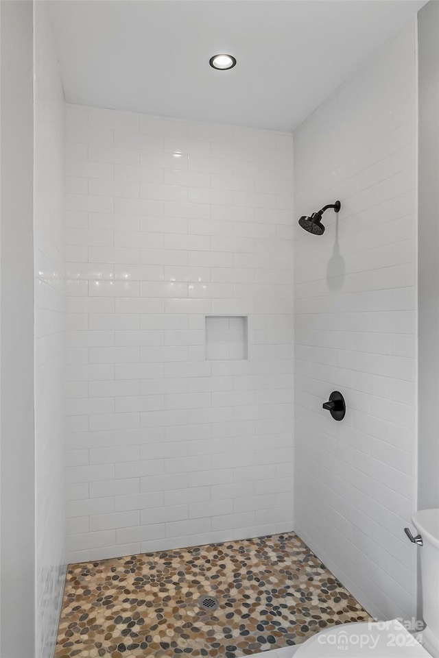 bathroom with toilet and a tile shower