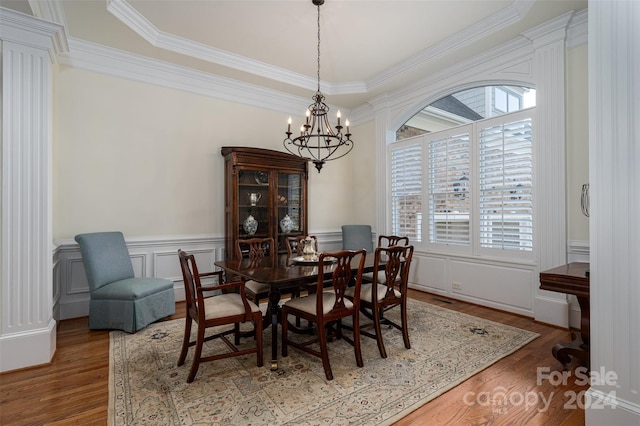 dining area featuring hardwood / wood-style flooring, a raised ceiling, crown molding, and a chandelier