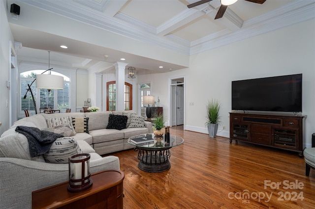 living room featuring hardwood / wood-style floors, beamed ceiling, coffered ceiling, ceiling fan, and crown molding