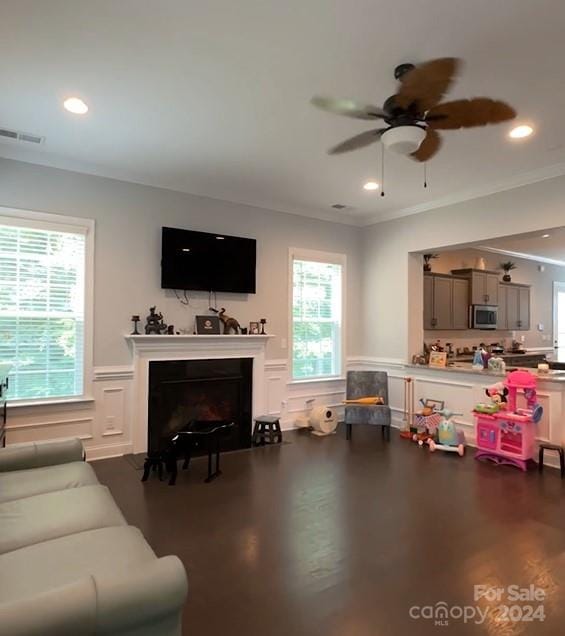 living area featuring visible vents, a fireplace, ceiling fan, wood finished floors, and wainscoting