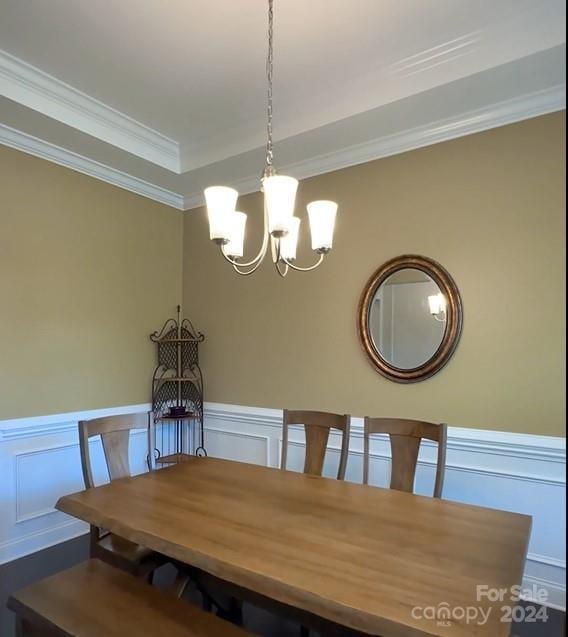 unfurnished dining area with a decorative wall, ornamental molding, a chandelier, and wainscoting