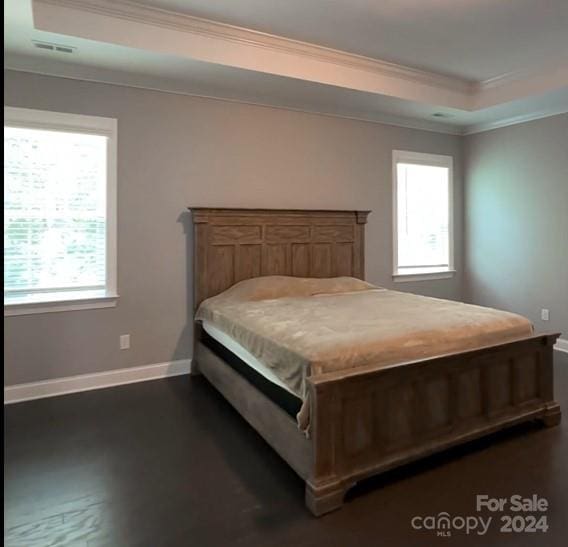 bedroom with multiple windows, visible vents, crown molding, and a raised ceiling