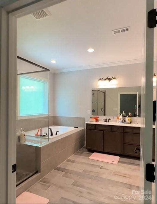 bathroom with crown molding, vanity, plus walk in shower, and hardwood / wood-style flooring