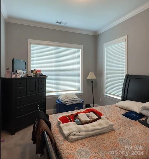 bedroom featuring carpet flooring, crown molding, and visible vents