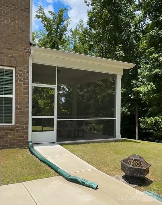 view of patio / terrace with a sunroom and a fire pit