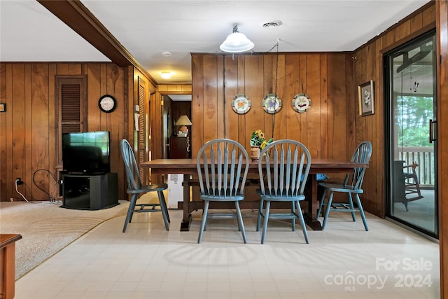 dining area with ornamental molding and wooden walls