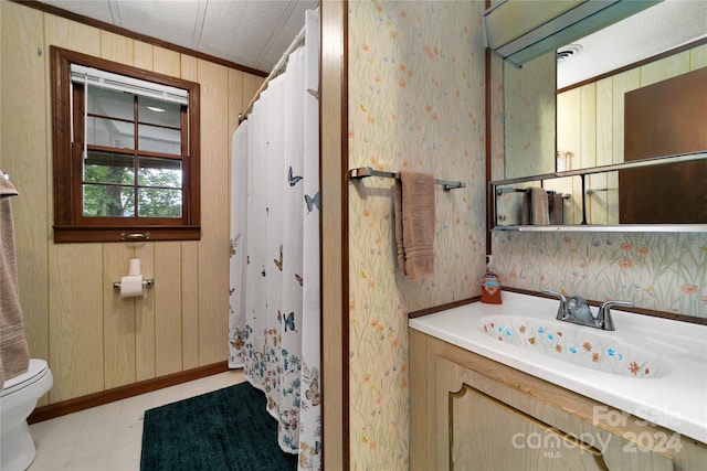 bathroom featuring crown molding, vanity, wood walls, and toilet