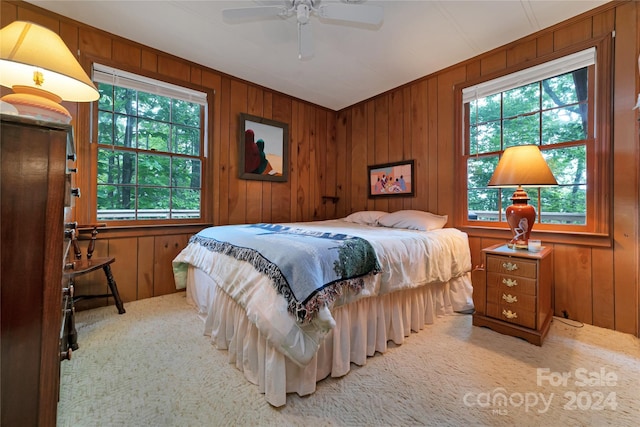 carpeted bedroom featuring ceiling fan and wooden walls