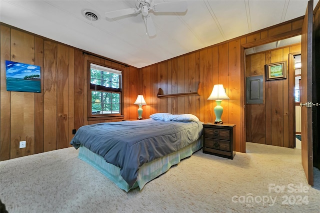 bedroom with carpet flooring, ceiling fan, and wood walls