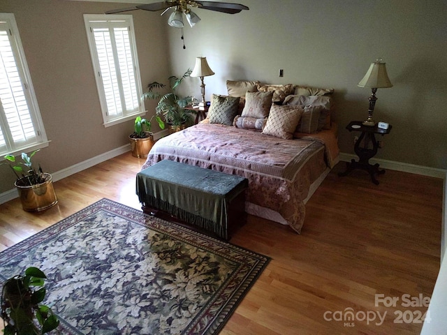 bedroom featuring ceiling fan, light hardwood / wood-style flooring, and multiple windows