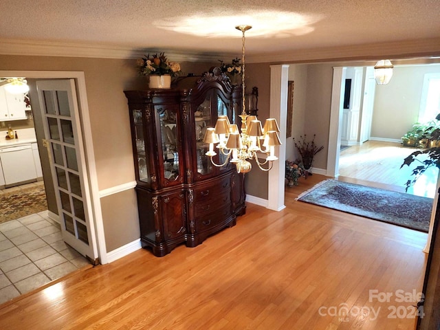 hallway with wood-type flooring, a textured ceiling, a chandelier, and ornamental molding