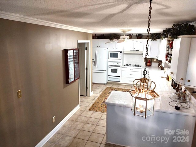 kitchen featuring tile counters, ornamental molding, white cabinets, and white appliances