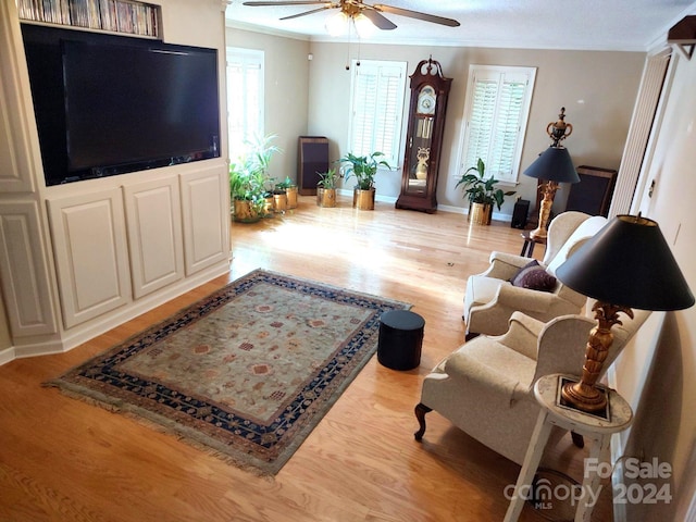 living room with ceiling fan, ornamental molding, and light hardwood / wood-style flooring