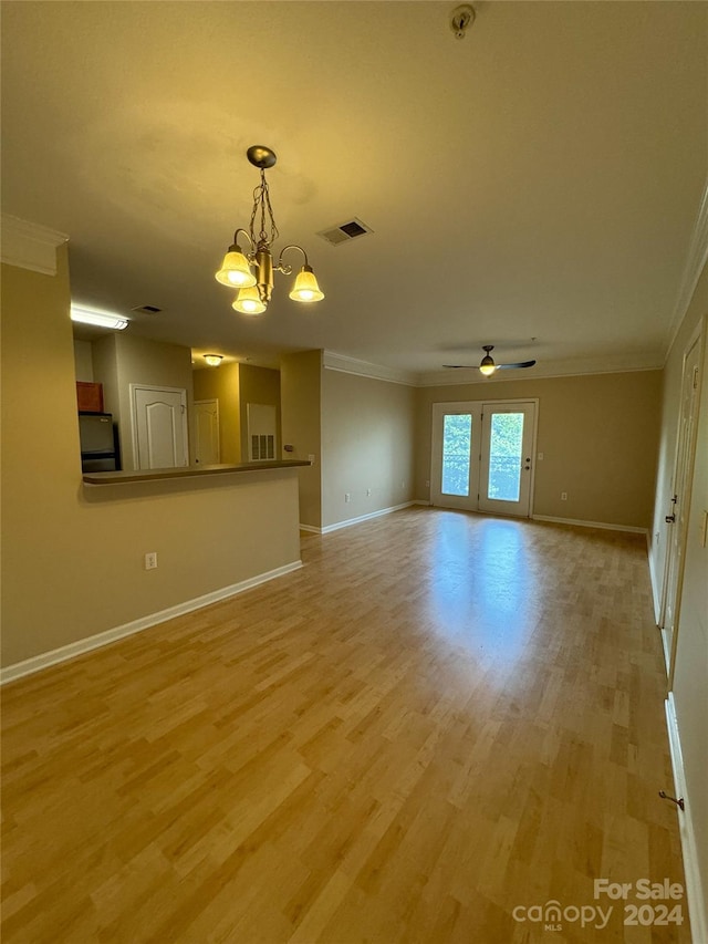 unfurnished living room featuring light wood-type flooring, crown molding, and ceiling fan with notable chandelier