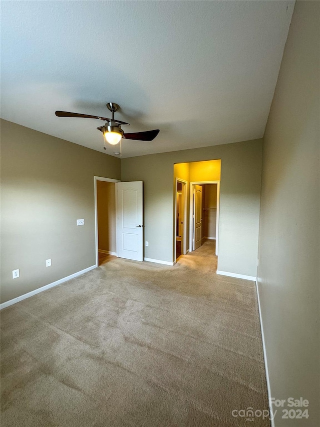 unfurnished bedroom with ceiling fan, light carpet, and connected bathroom