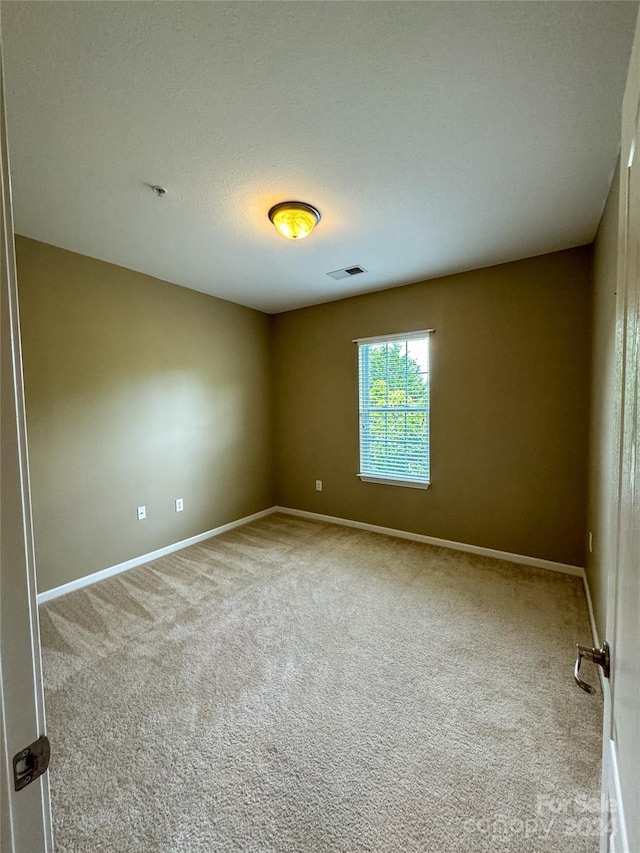 carpeted empty room featuring a textured ceiling