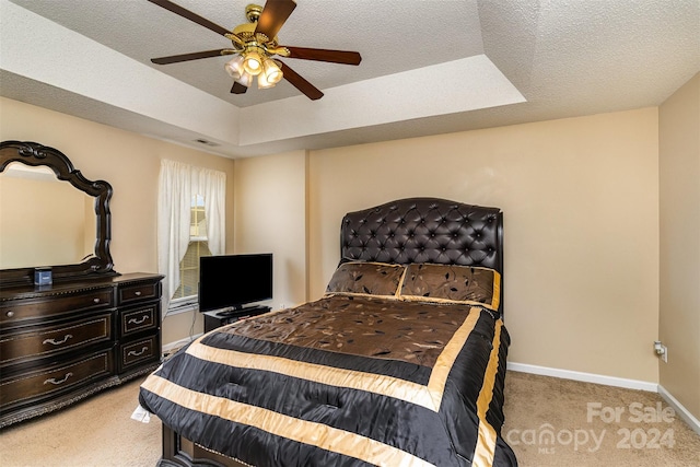 carpeted bedroom with a textured ceiling, a tray ceiling, and ceiling fan