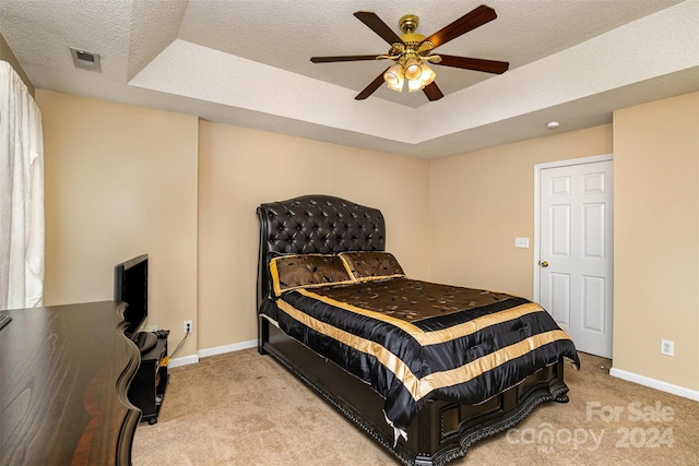 carpeted bedroom featuring a raised ceiling, ceiling fan, and a textured ceiling