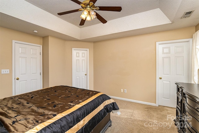 bedroom featuring ceiling fan, a raised ceiling, light colored carpet, and a textured ceiling