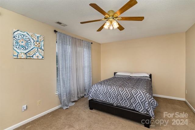 bedroom featuring ceiling fan, light colored carpet, and a textured ceiling