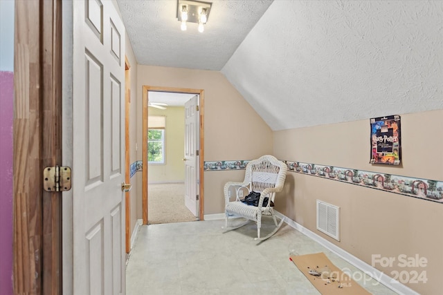 sitting room featuring a textured ceiling and lofted ceiling