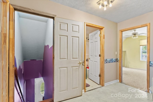 hallway with light colored carpet and a textured ceiling