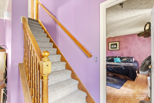 stairs with hardwood / wood-style flooring and a textured ceiling