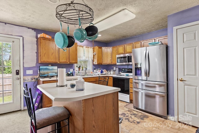 kitchen with a kitchen bar, sink, a center island, and stainless steel appliances