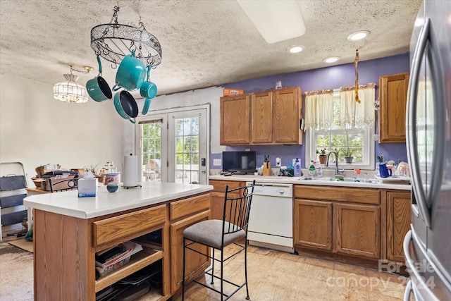 kitchen featuring sink, hanging light fixtures, white dishwasher, and a textured ceiling