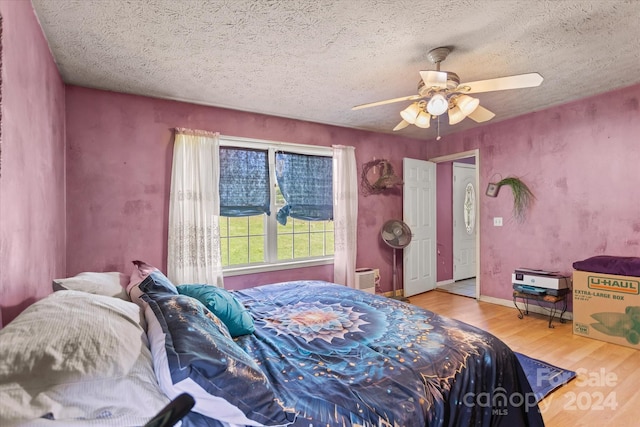 bedroom featuring light wood-type flooring, a textured ceiling, and ceiling fan