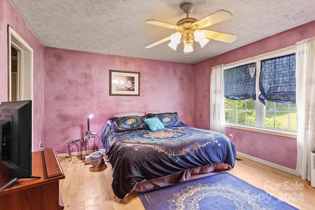 bedroom with ceiling fan, light hardwood / wood-style flooring, and a textured ceiling