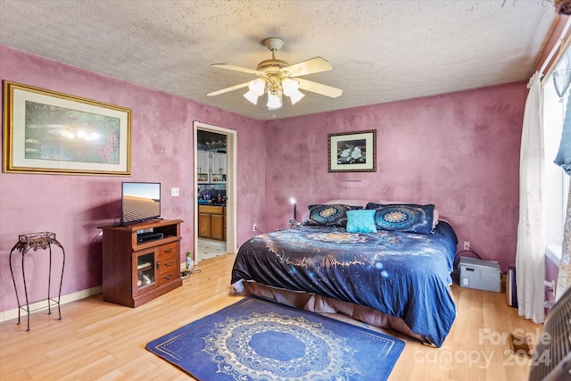 bedroom featuring ceiling fan, connected bathroom, hardwood / wood-style flooring, and a textured ceiling