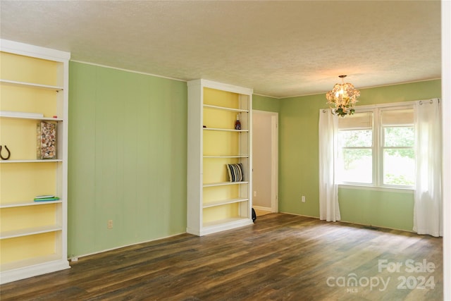 spare room featuring a chandelier, a textured ceiling, and dark hardwood / wood-style floors