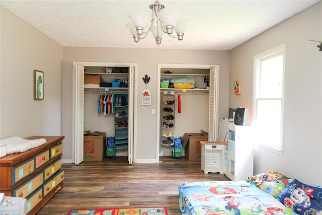 bedroom with multiple closets, an inviting chandelier, and dark hardwood / wood-style flooring