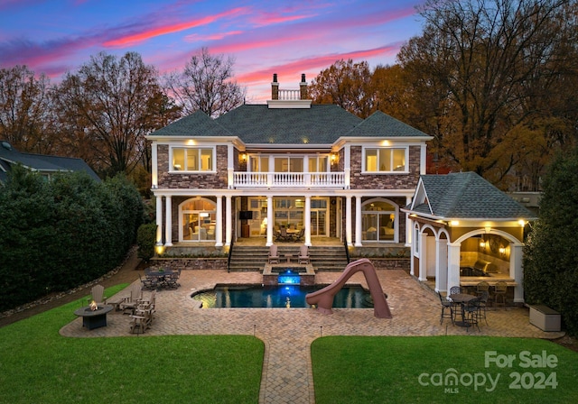 back house at dusk with a patio, a balcony, and an outdoor fire pit