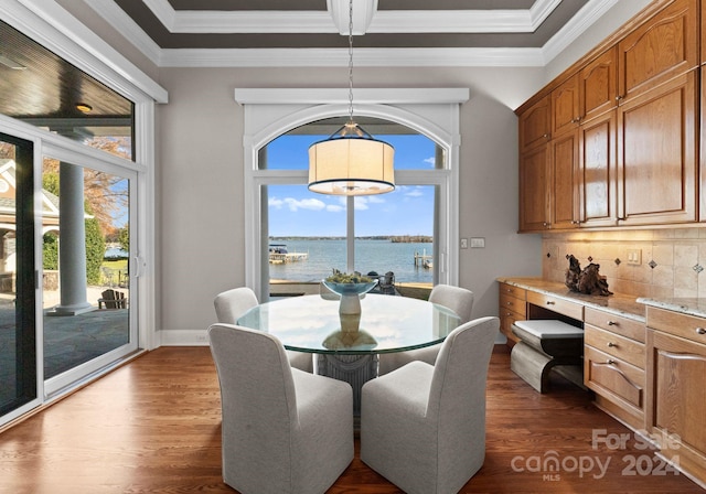 dining room featuring dark hardwood / wood-style flooring, a water view, and a healthy amount of sunlight