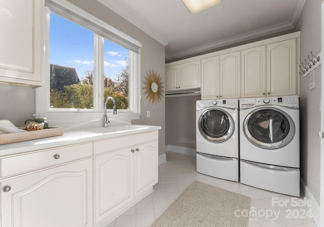 clothes washing area featuring washing machine and clothes dryer, sink, light tile patterned floors, and cabinets