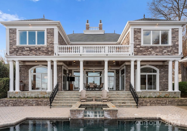 rear view of house featuring an in ground hot tub and a patio area